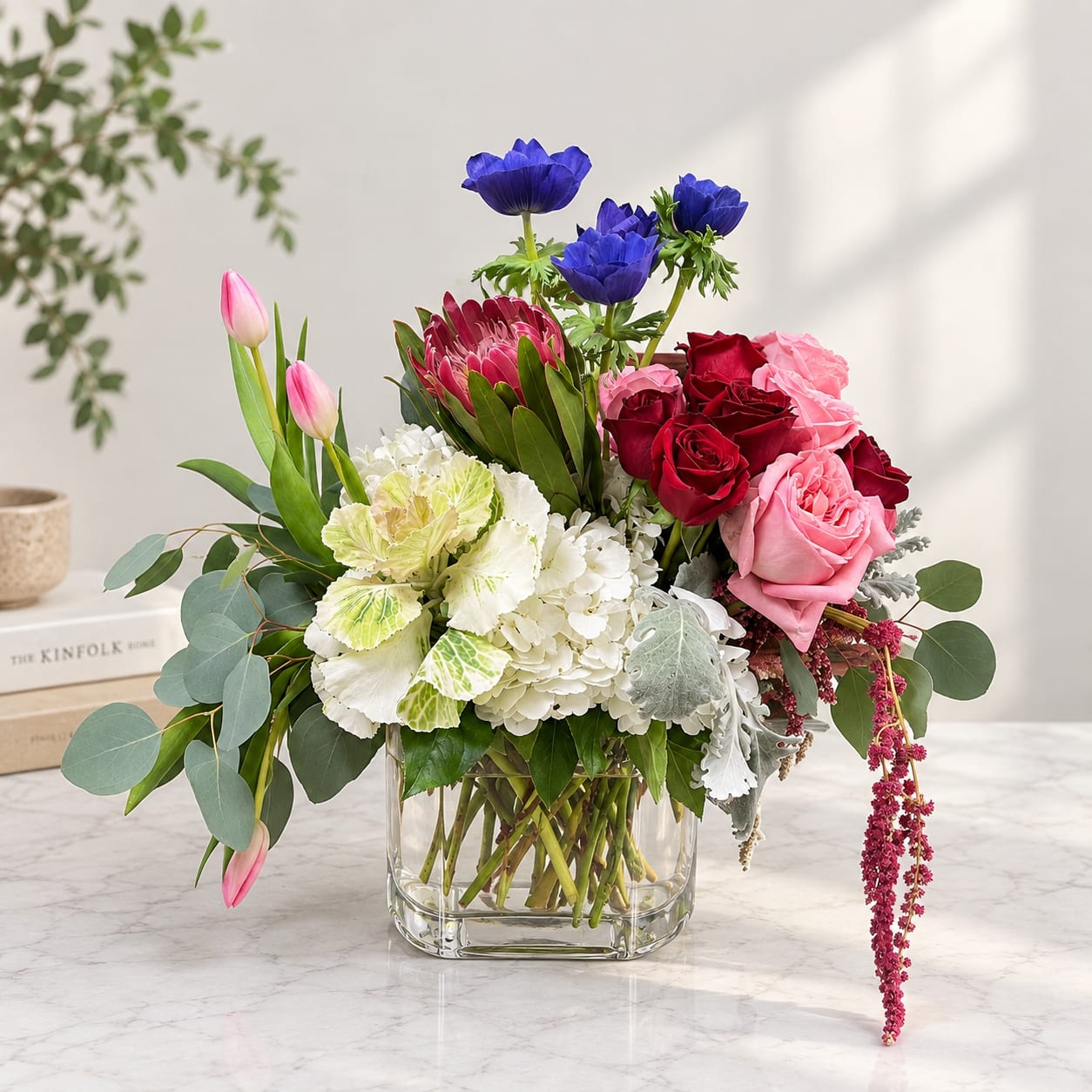 Mixed bouquet in a clear square vase with pink, red, white, and blue flowers