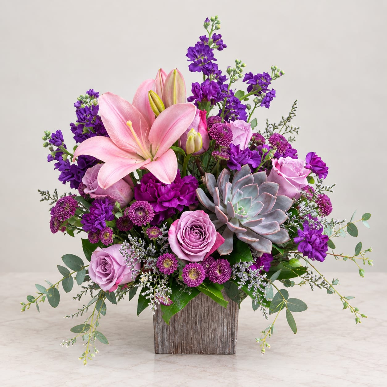 Pink lilies and roses with purple flowers in a wooden vase