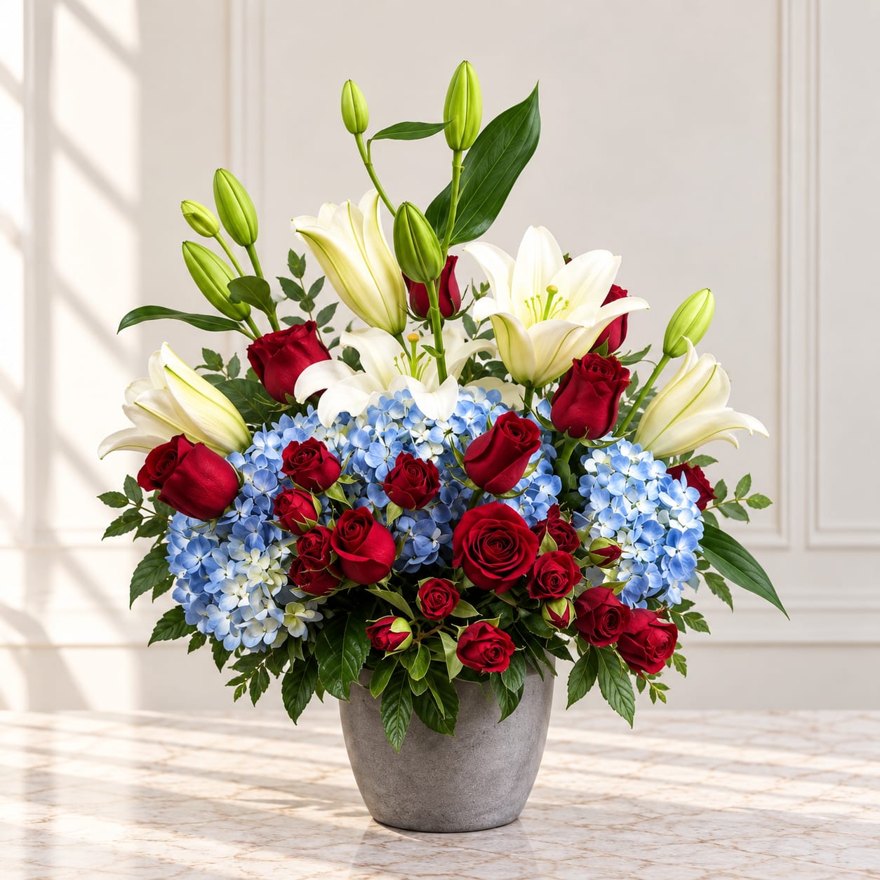 Red roses, white lilies, and blue hydrangeas in a gray vase