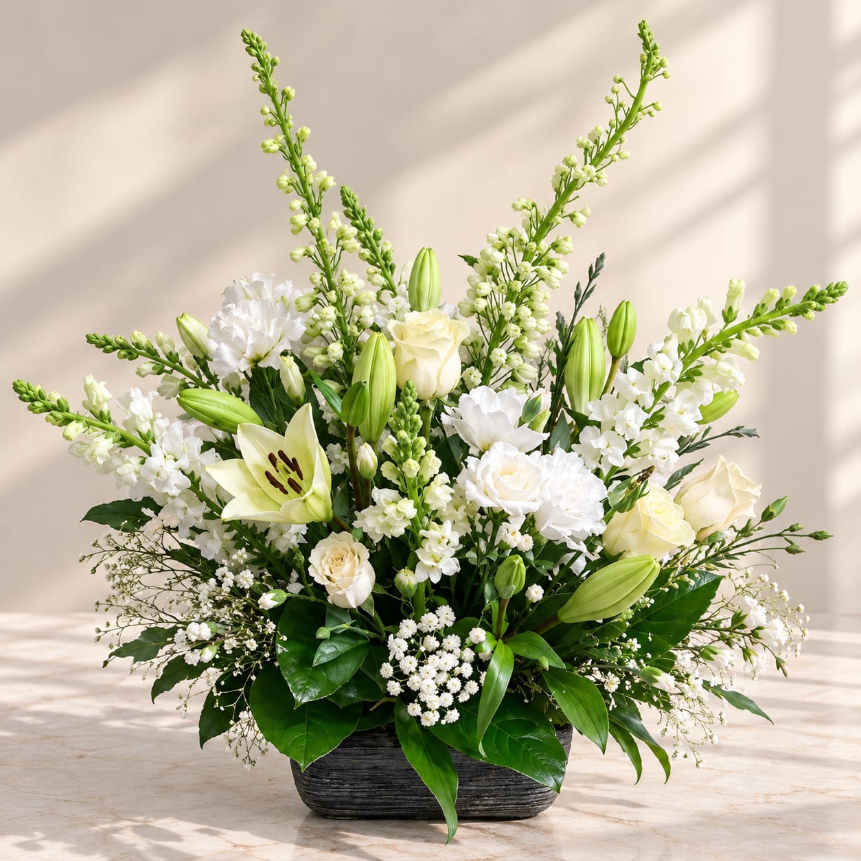 White lilies and roses arranged in a low dark vase