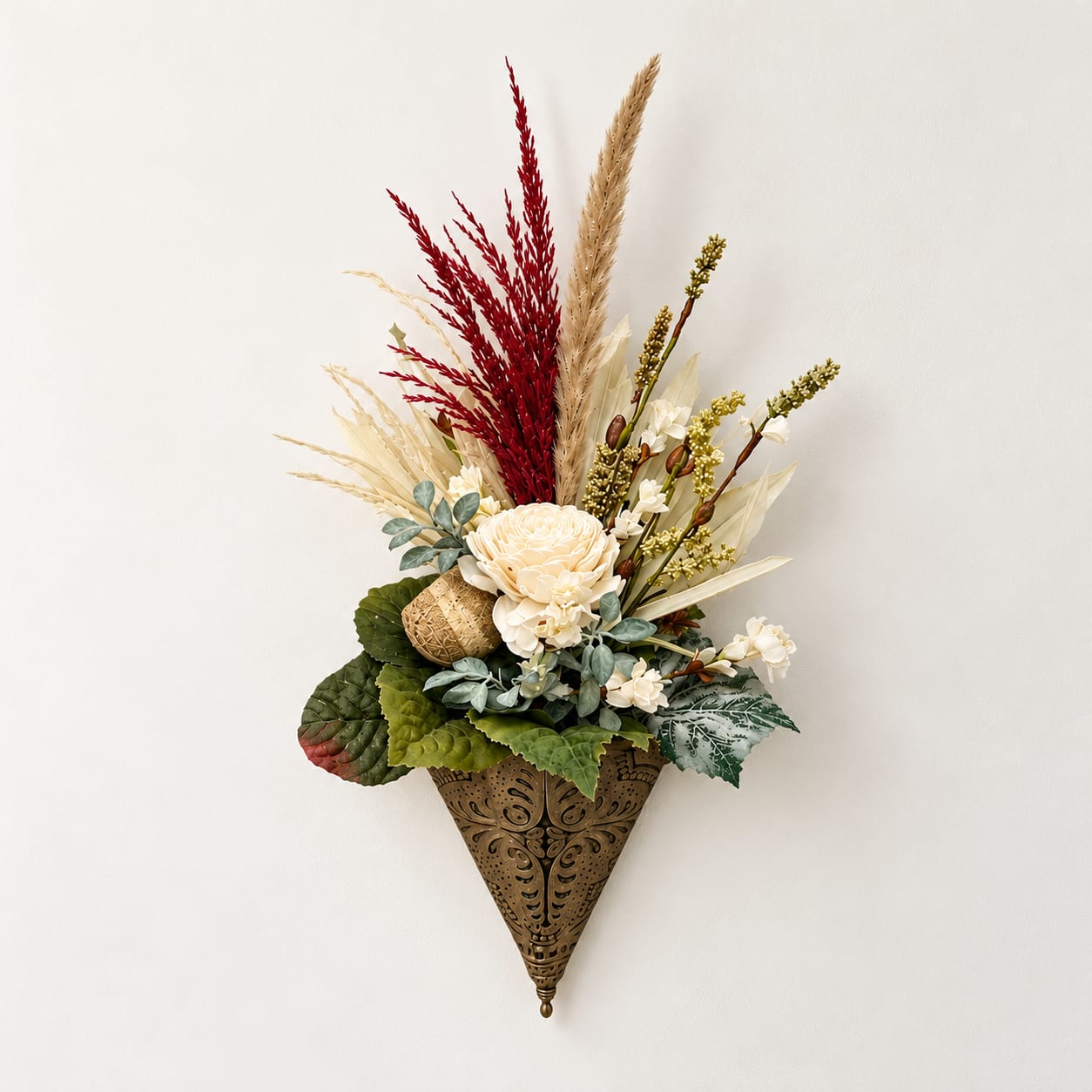 Wall-mounted floral arrangement with cream blooms and red dried grasses in a decorative cone holder