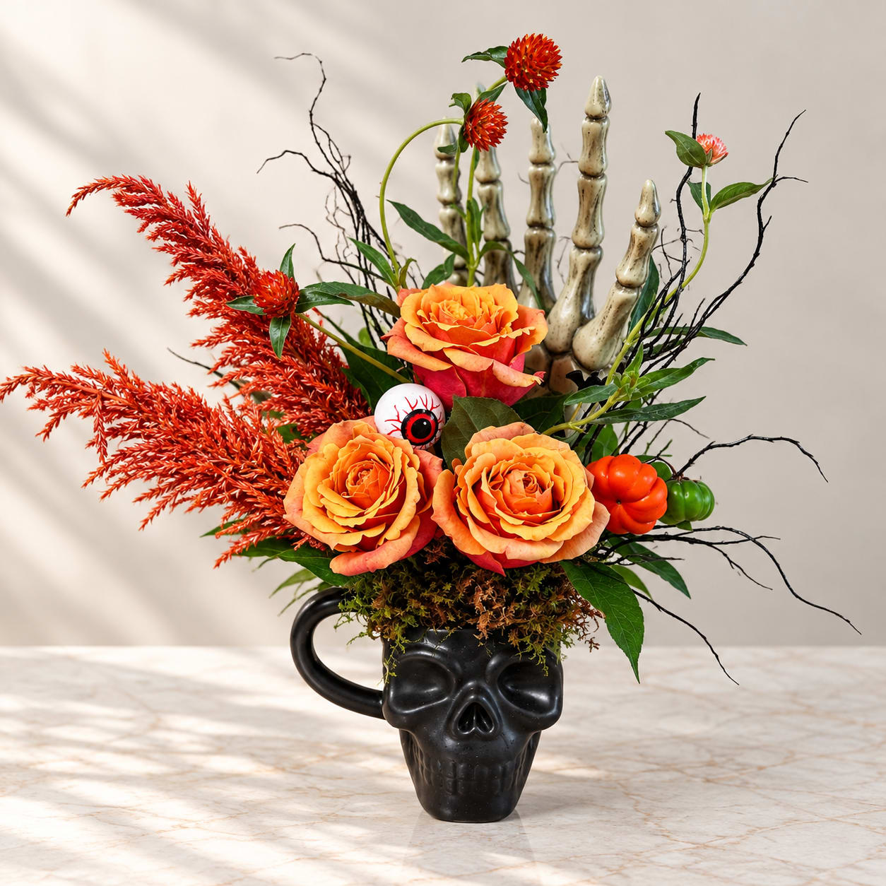 Orange roses in a black skull mug with Halloween accents
