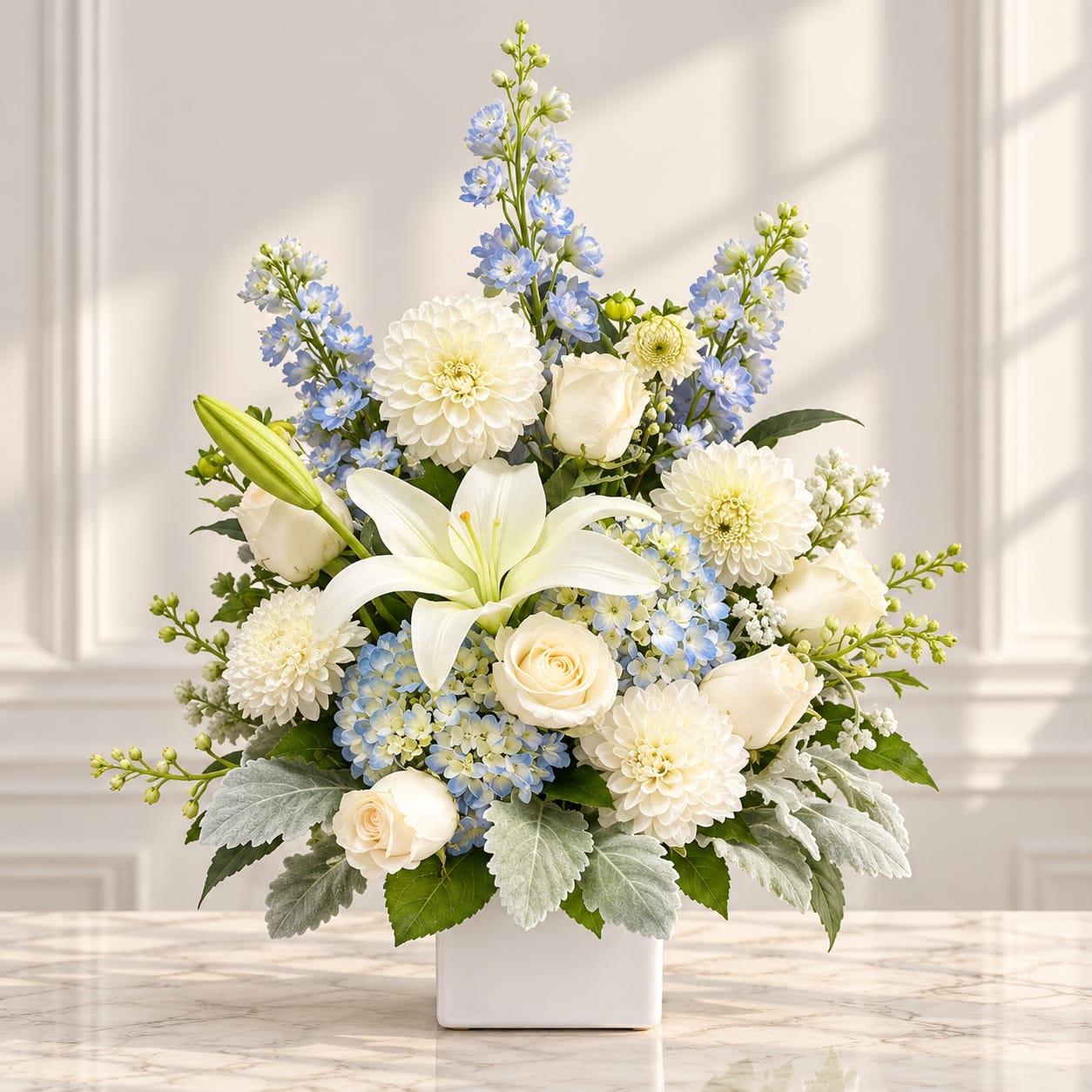 White and blue floral arrangement in a square white vase