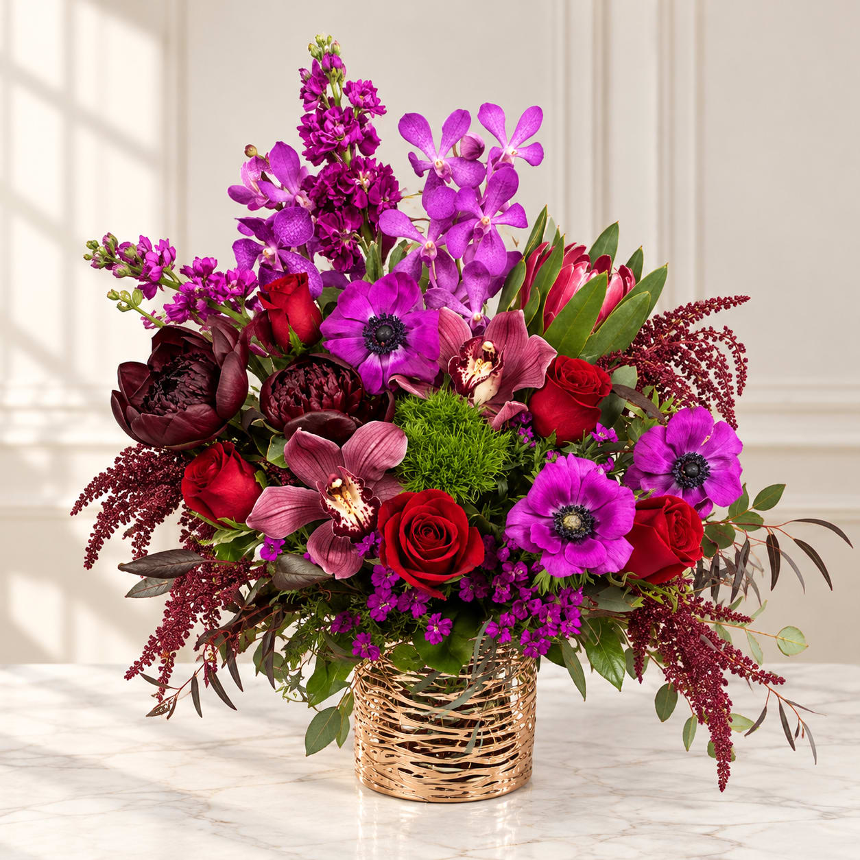 Bright bouquet of purple and red flowers in a gold basket vase
