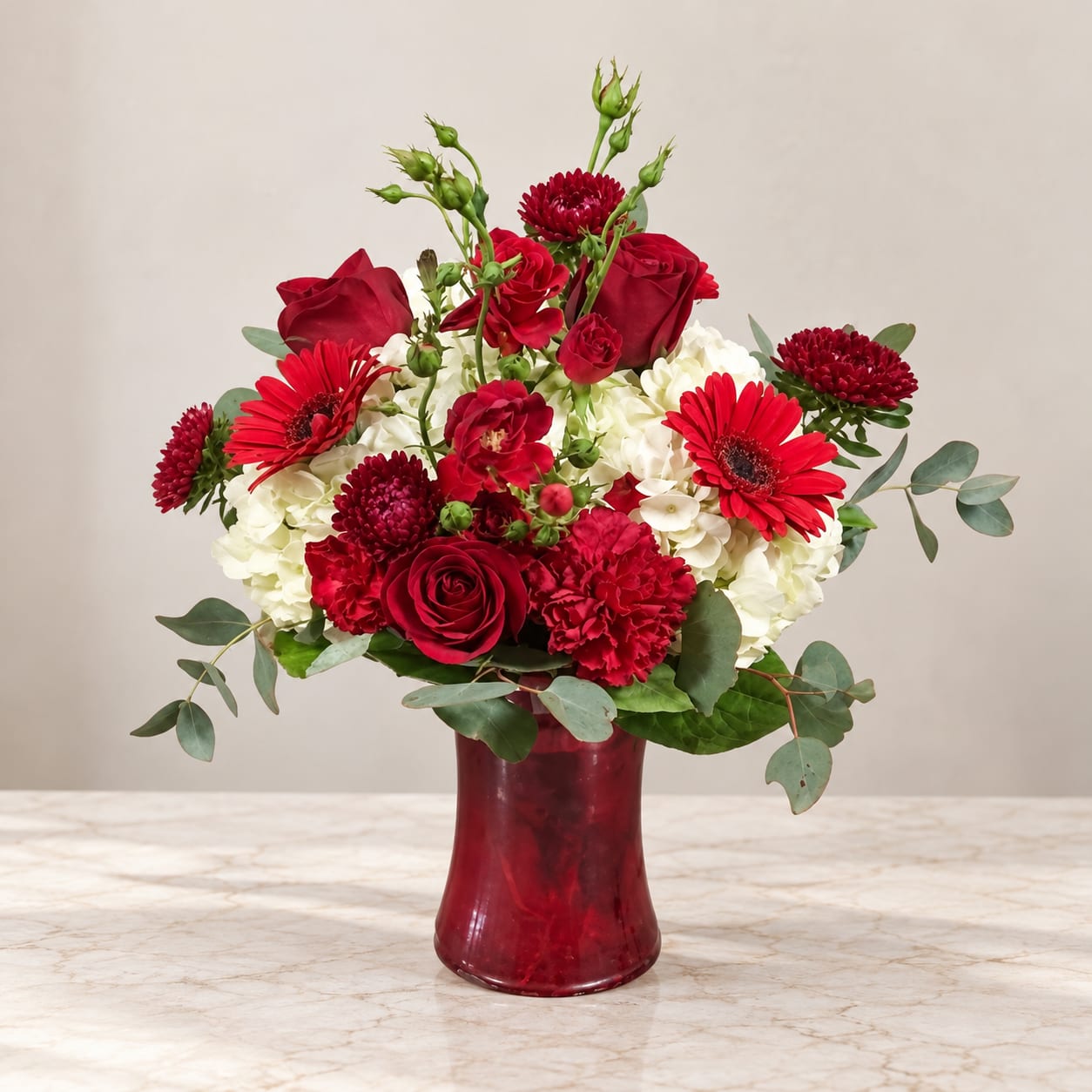 Red and white flower arrangement in a red vase
