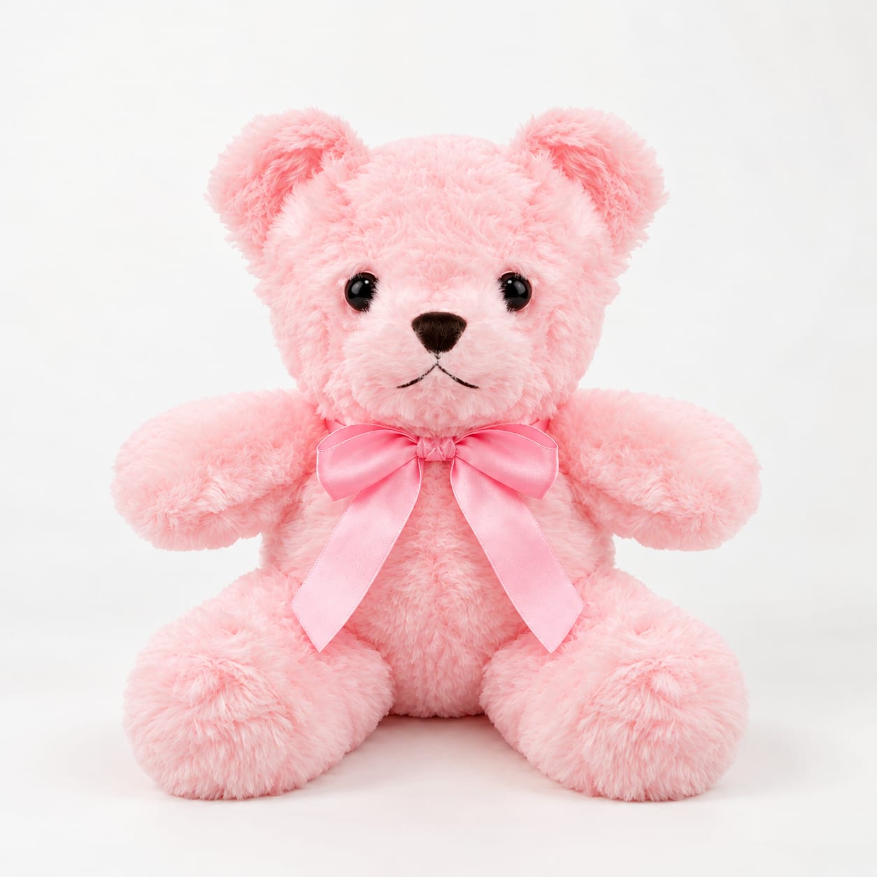 Pink plush teddy bear with a satin bow on a white background