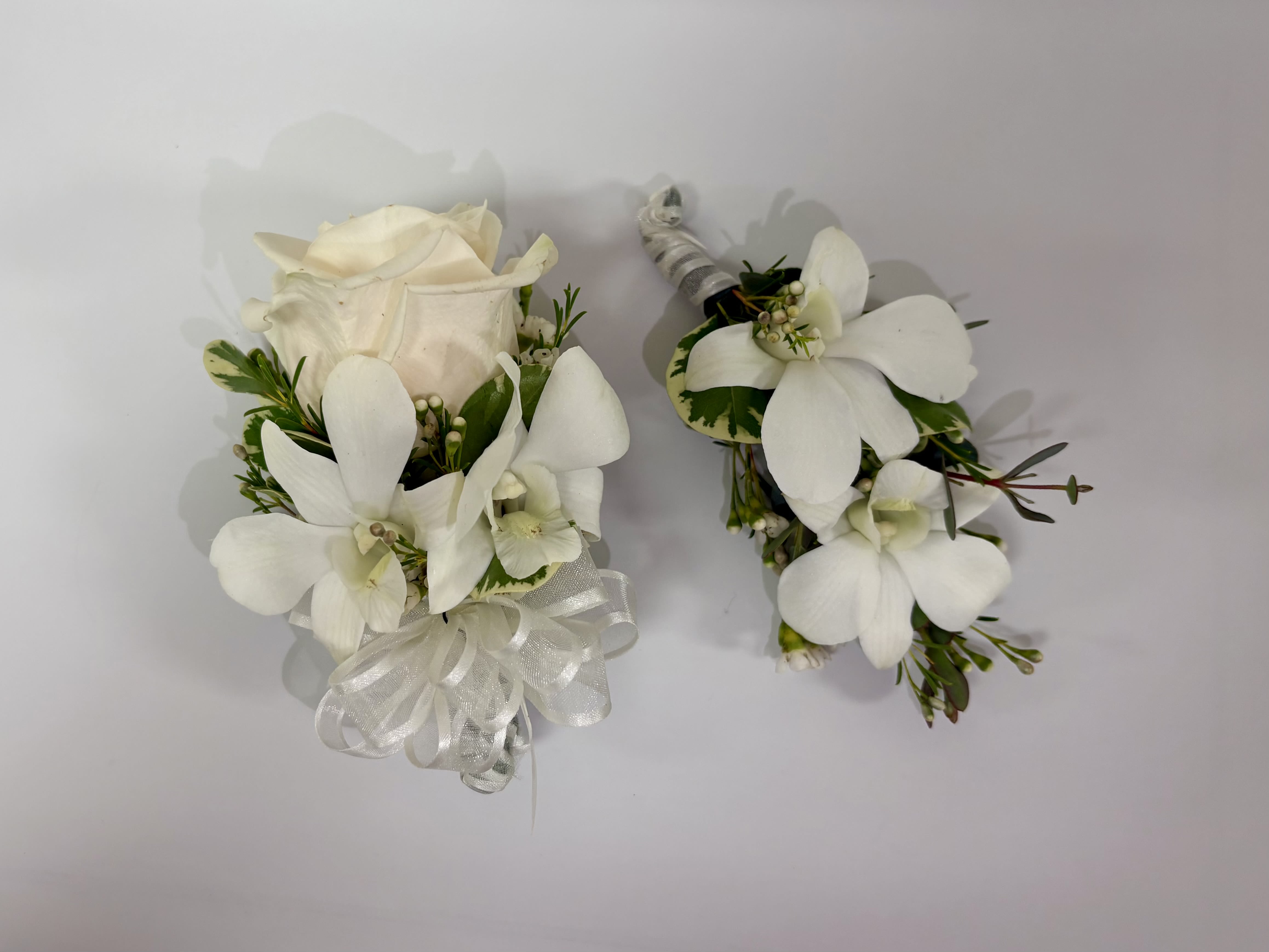 Standard Rose and Dendrobium Orchids Corsage and Boutonniere  - Recipe: Regular rose and Dendrobium Orchids with Wax Flower Filler. Rose color available: white, ivory, red, yellow, lavender, pink Dendorbium orchid color available: white or pink  PLEASE READ BEFORE PURCHASE:  Boutonniere purchase only- standard Corsage purchaseonly- deluxe Boutonniere and corsage set- premium.  Please specify color rose and ribbon in special instructions during check out. Send us a picture of the color dress/ tux to our email with order number to best match ribbon at hello@flowerfinesse.com ACCENTS ARE OUT OF STOCK. Pick up only available.