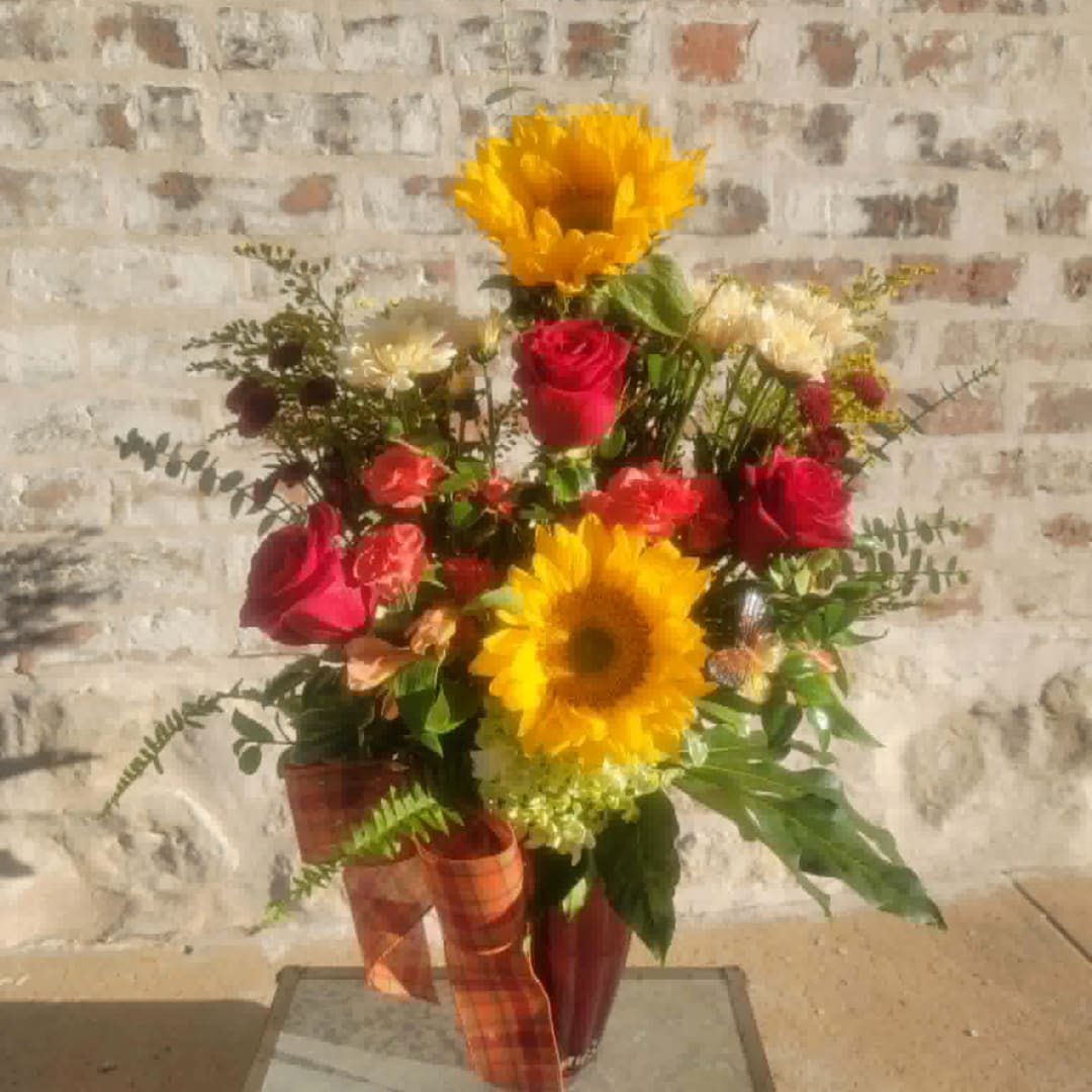 Bouquet of sunflowers and red roses in a vase with plaid ribbon