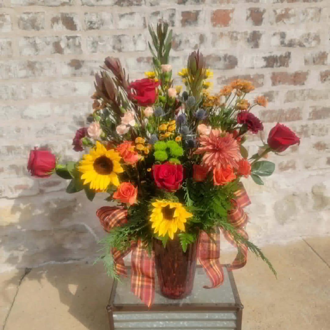 Mixed bouquet with red roses and sunflowers in a glass vase
