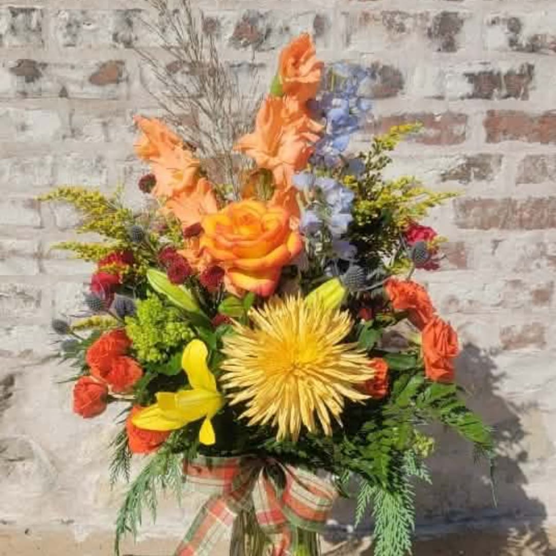 Colorful bouquet with orange, yellow, and blue flowers in a wrapped vase