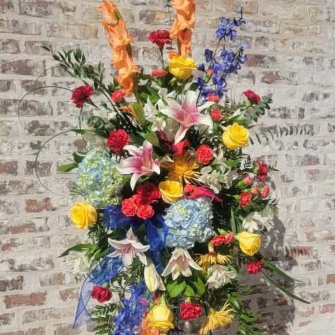 Tall mixed floral arrangement with lilies, roses, and blue flowers