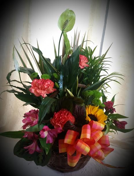 Mixed floral basket with carnations, sunflower, and tropical foliage