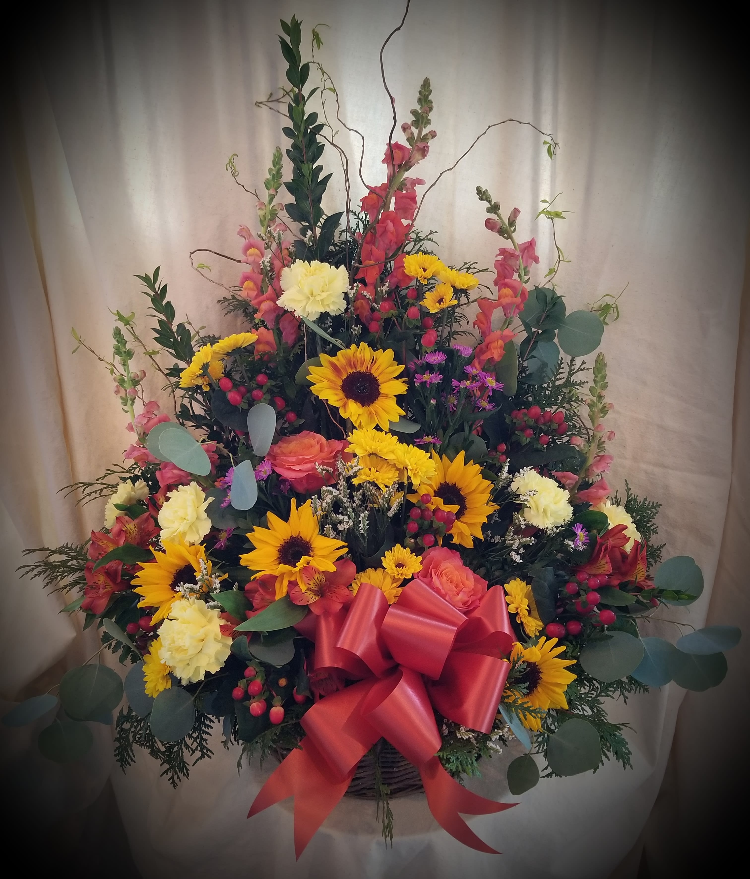 Large mixed flower basket with sunflowers, roses, and a red bow