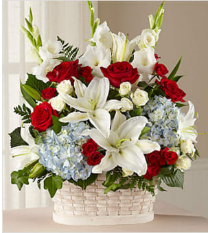 Basket arrangement of red roses, white lilies, and blue hydrangeas