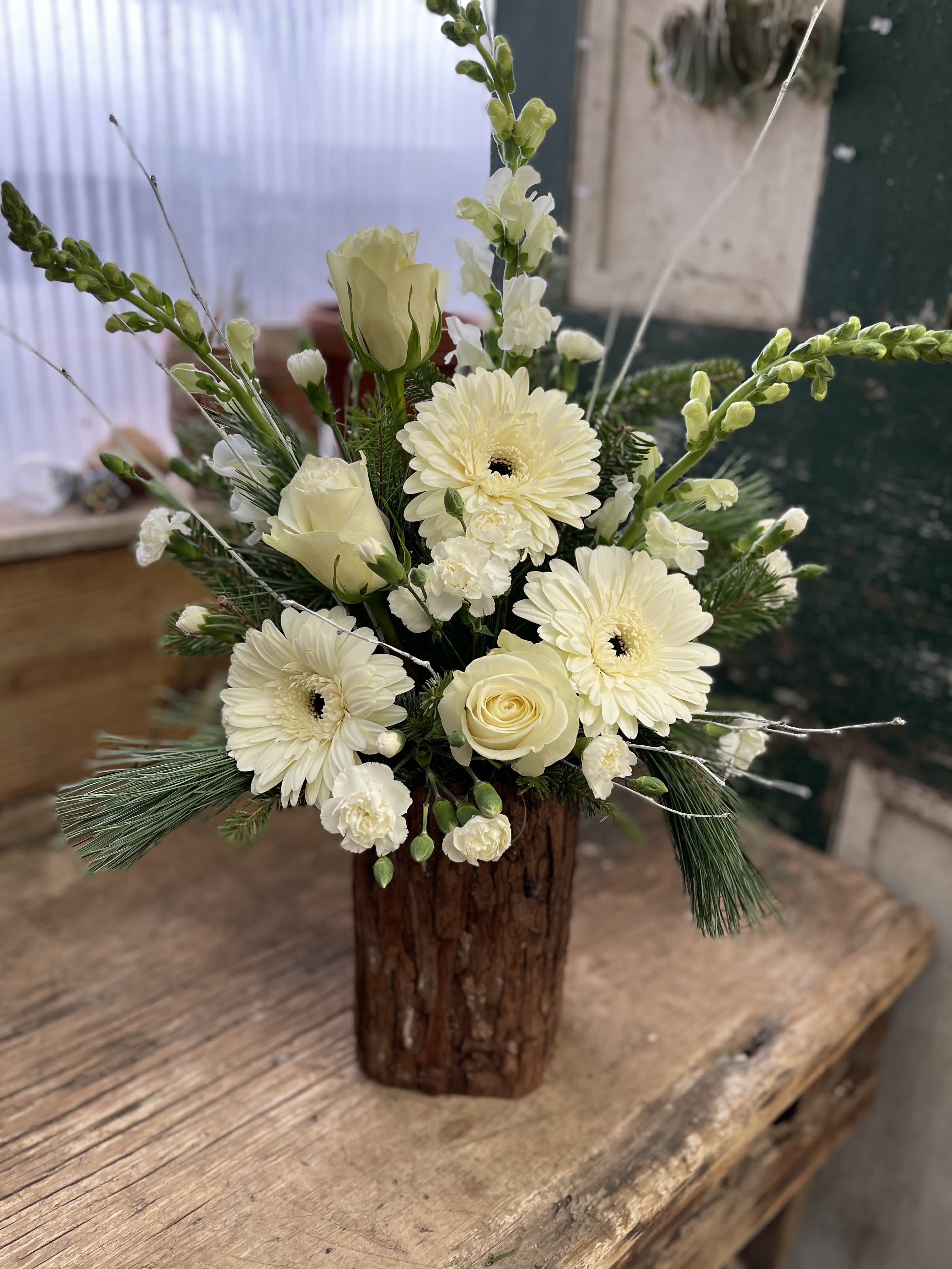 Cream floral arrangement in a rustic wooden vase