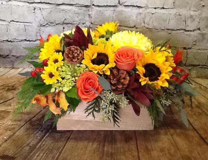 Floral feast - A long and low wooden box makes a perfect centerpiece, filled with a brilliant array of vibrant autumn blooms such as sunflowers, hydrangea, berries, roses and fragrant cedar and eucalyptus 