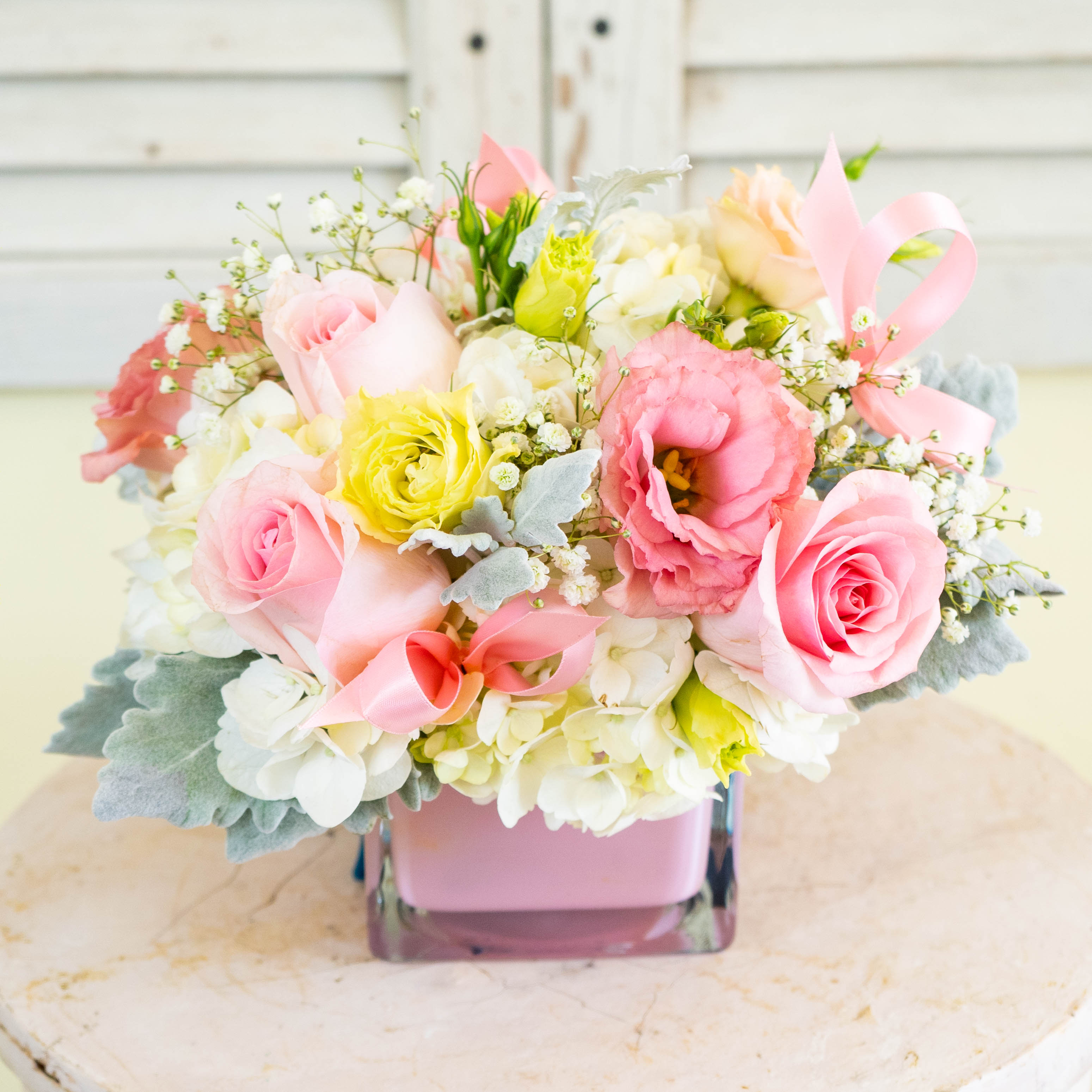 Pink and white bouquet in a square glass vase with ribbon accents