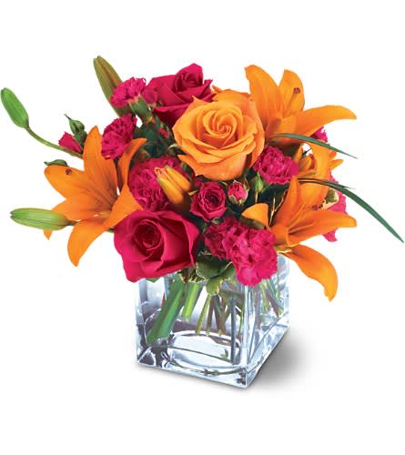 Orange lilies and pink roses in a clear square vase