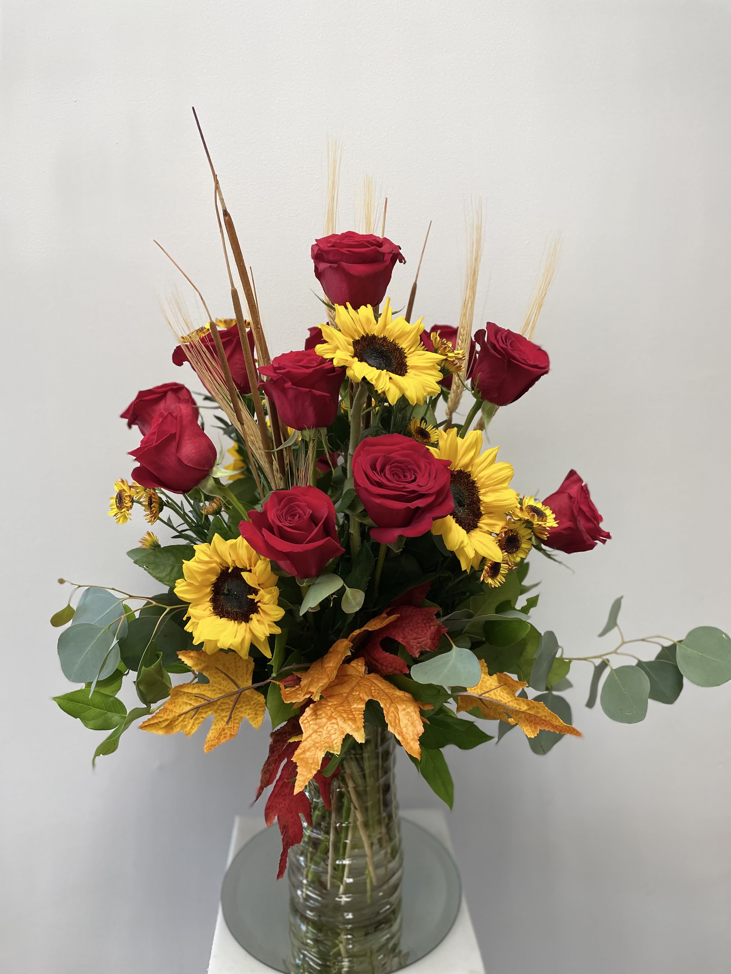 Red roses and yellow sunflowers in a clear glass vase