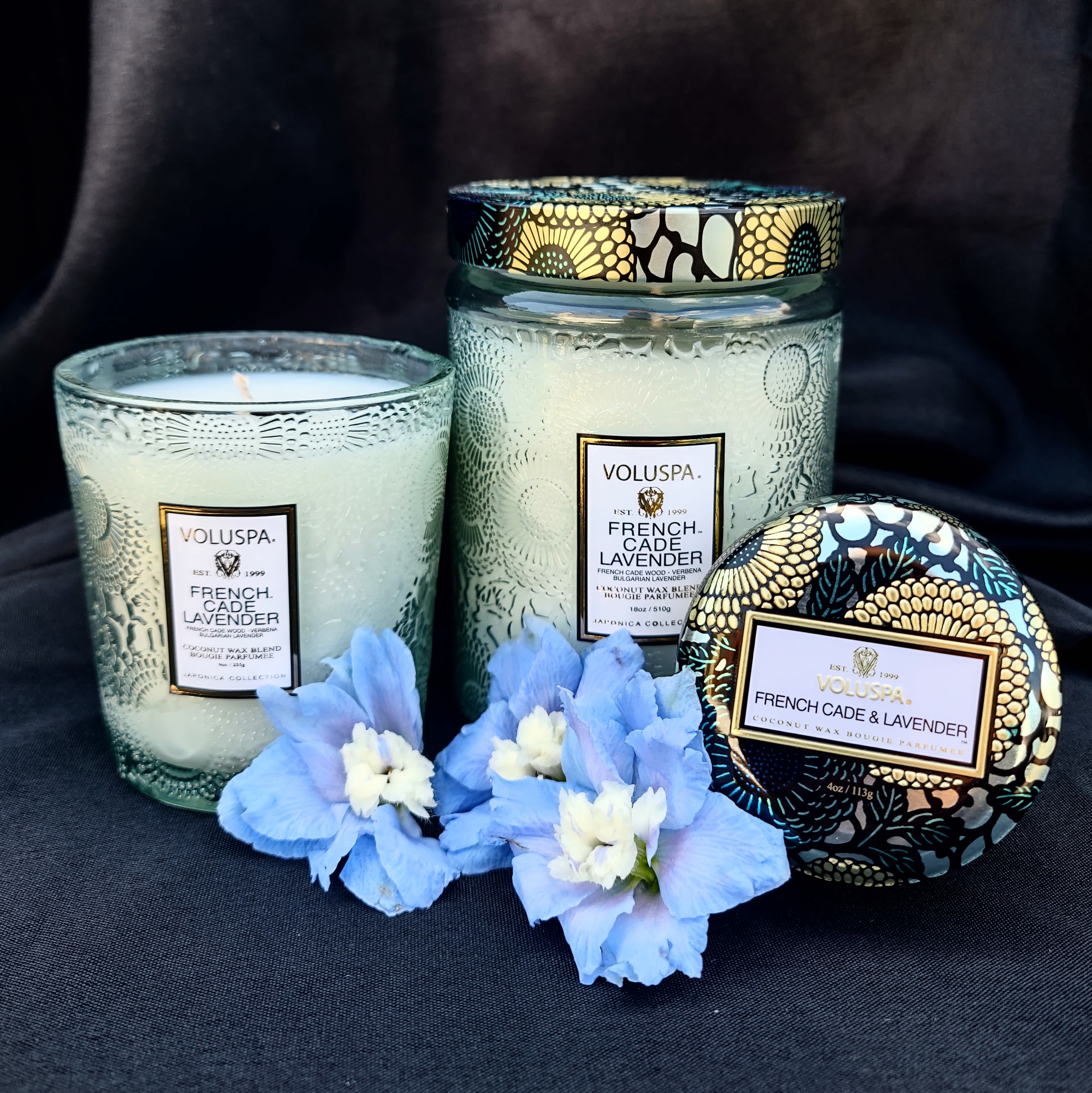 Three lavender-scented candles with blue flowers in front