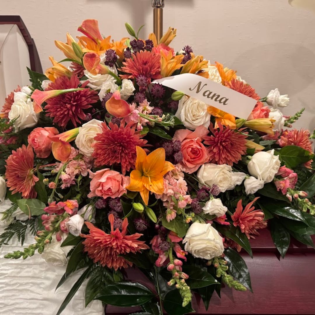Large mixed bouquet with orange, pink, and white flowers and a name card