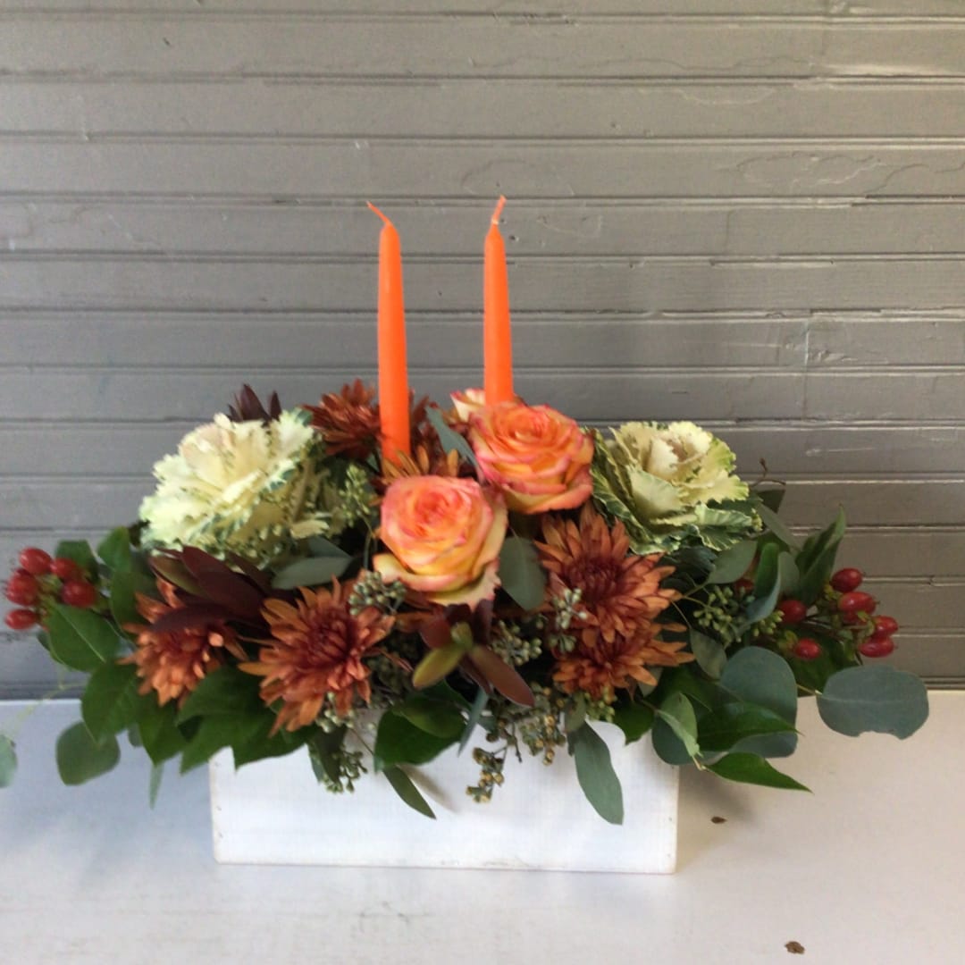 Orange roses and mums arranged with two orange candles in a white box