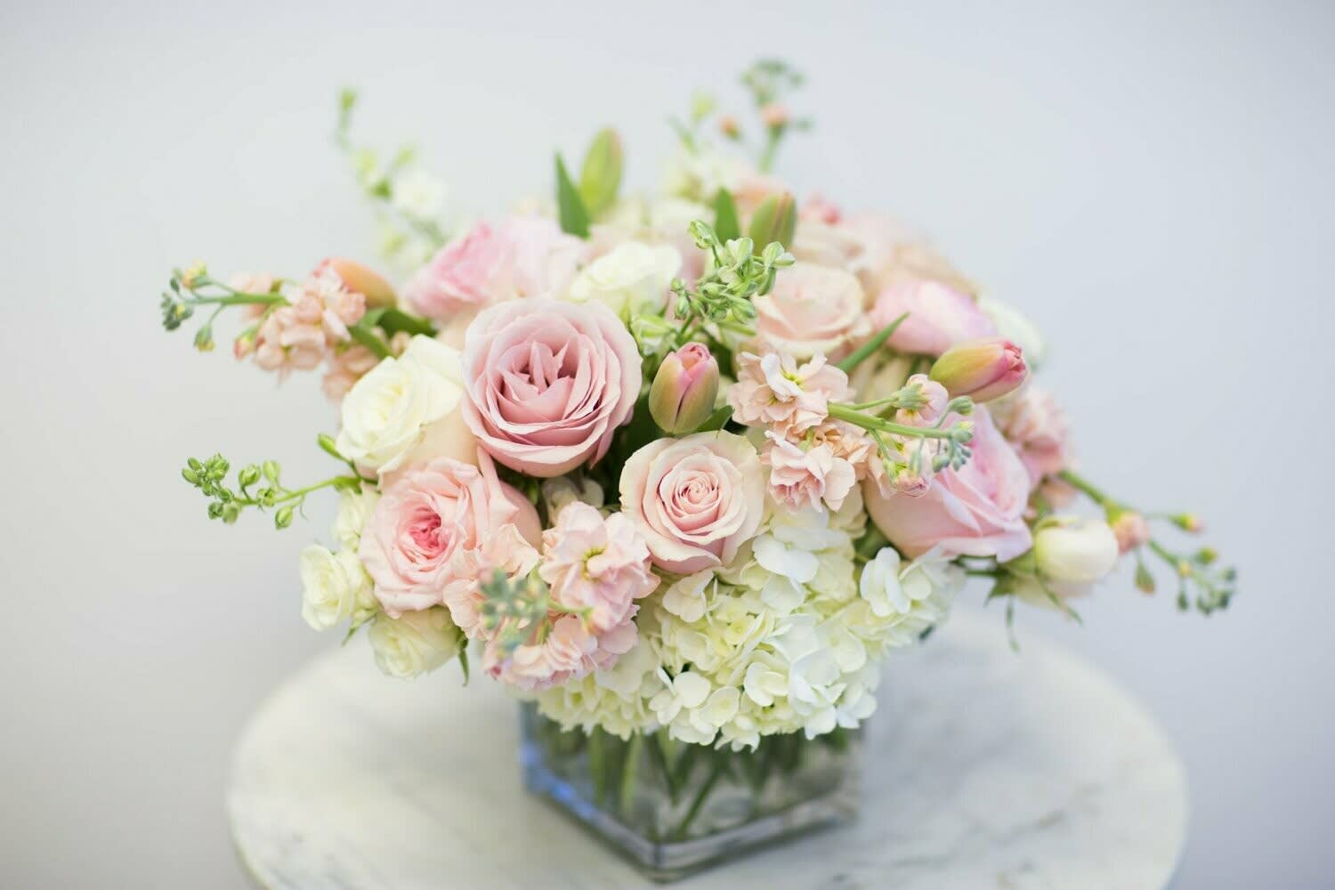 Blush pink and white bouquet in a square glass vase