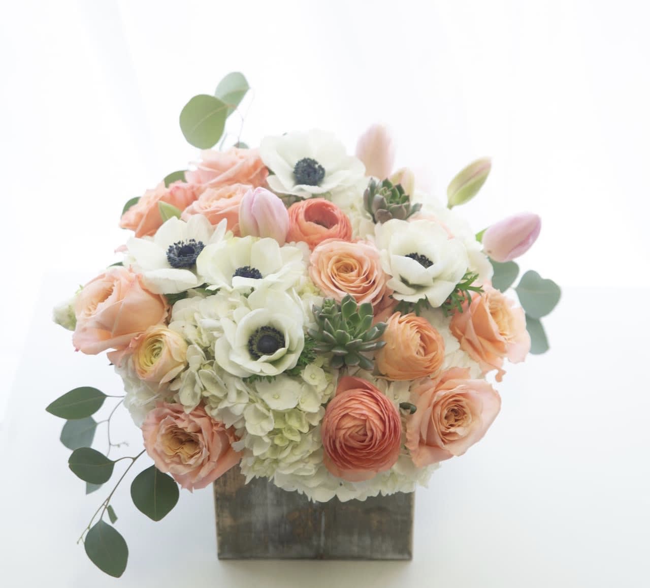 Peach and white floral arrangement in a square wooden container
