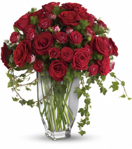 Red roses arranged in a clear glass vase with trailing ivy