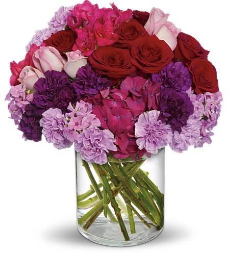 Bouquet of red roses and pink-purple flowers in a clear glass vase