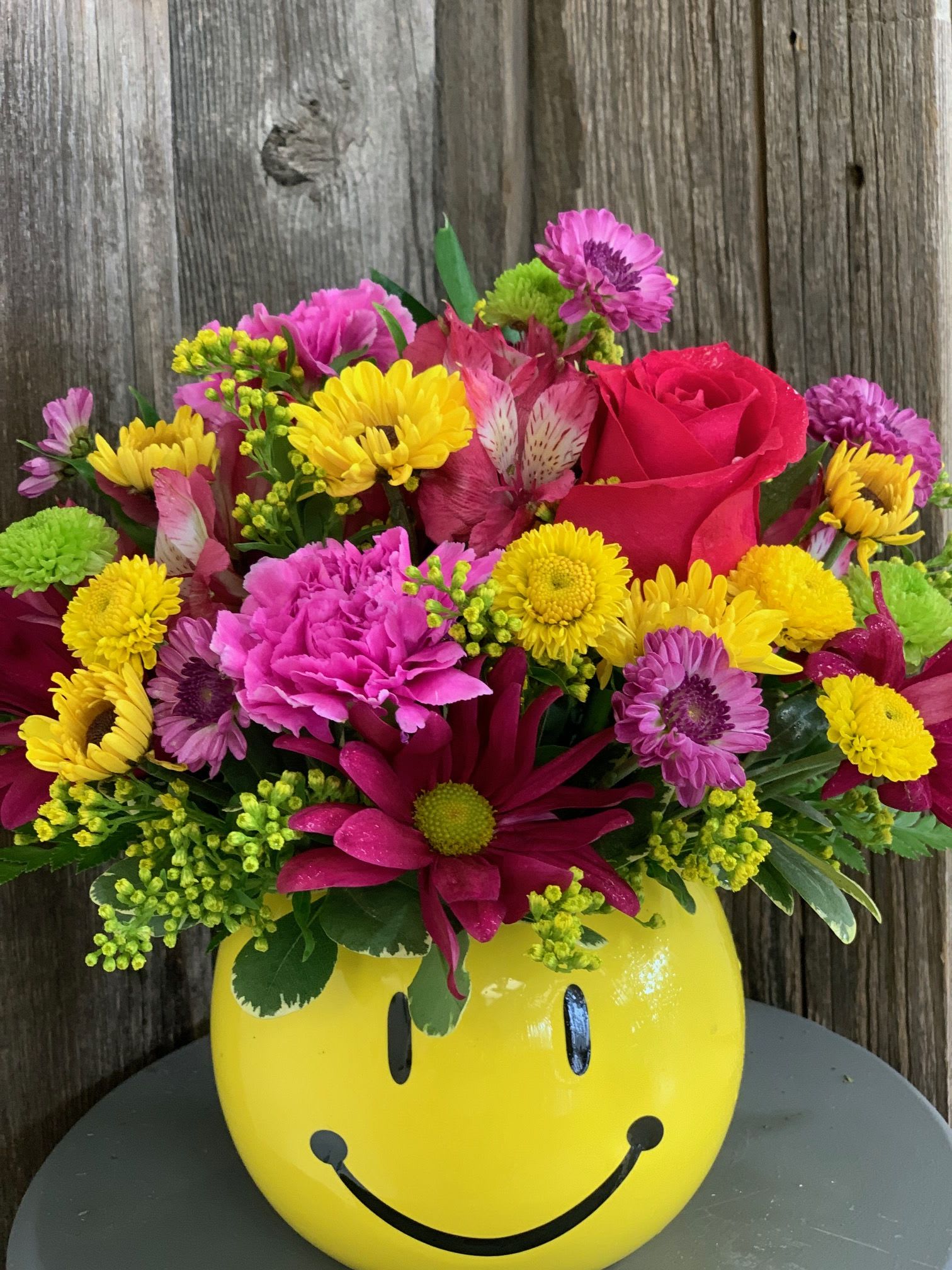 Bright mixed bouquet in a yellow smiley-face vase