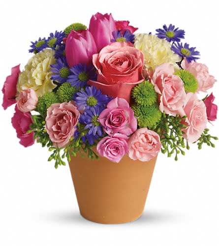 Pink roses and purple daisies arranged in a tan cone vase
