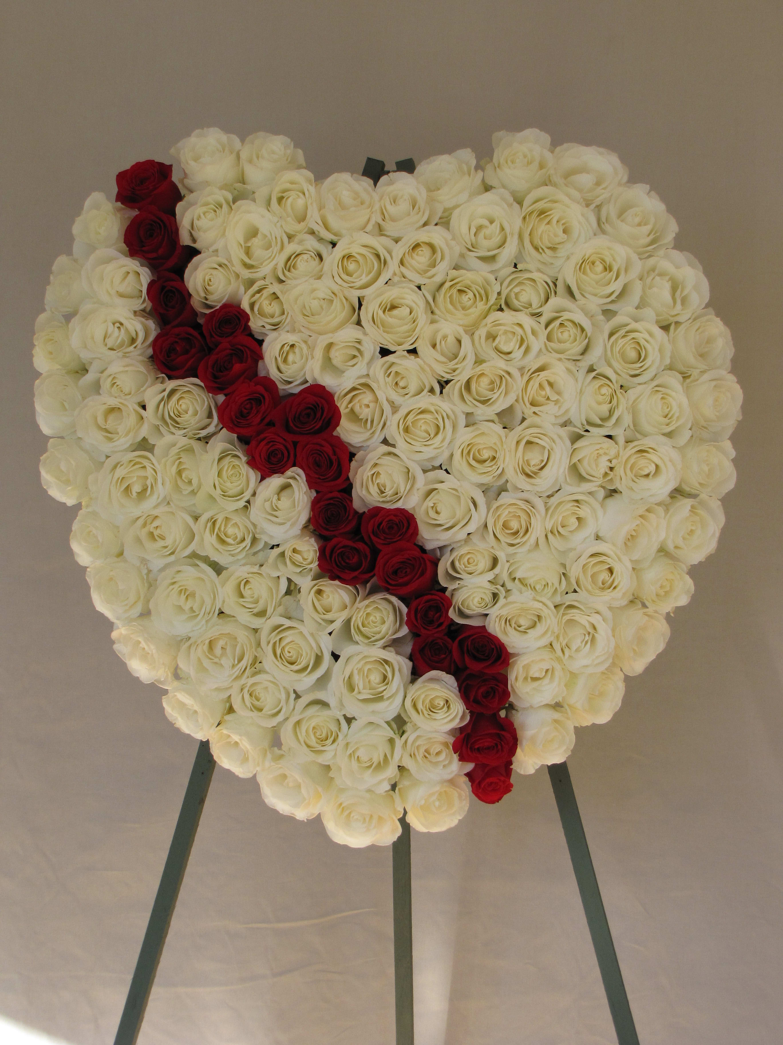 Heart-shaped rose arrangement with a red diagonal stripe on an easel