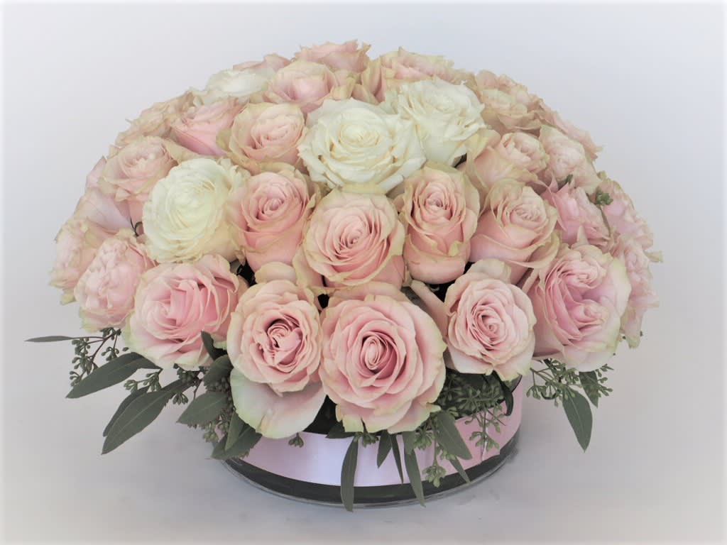 Round bouquet of pale pink and white roses in a low container