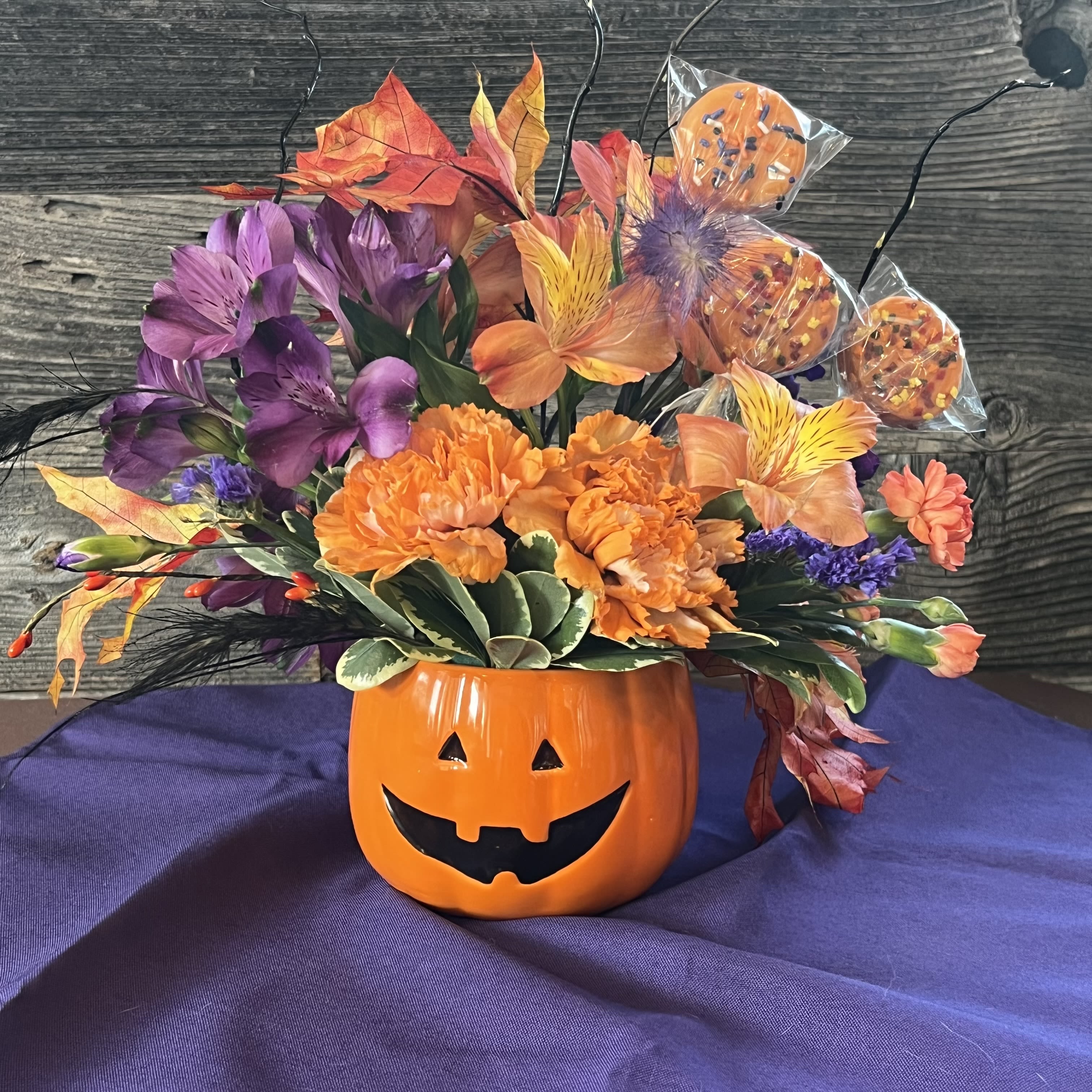 Halloween bouquet in a jack-o'-lantern mug with orange and purple flowers