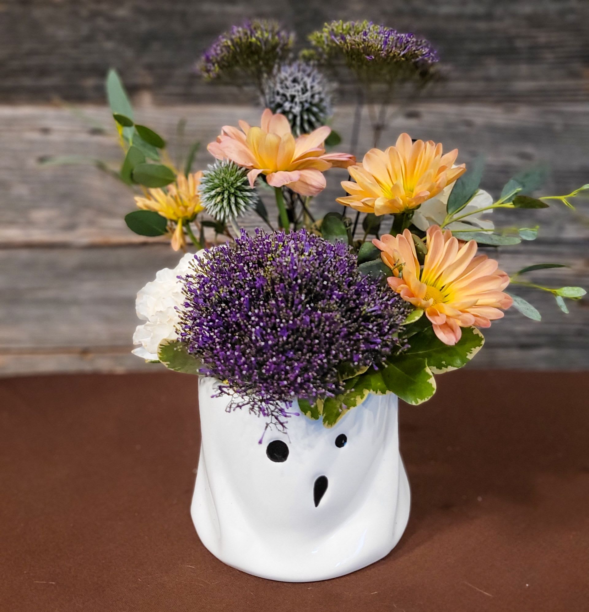 Peach and purple flowers arranged in a white ghost-shaped vase