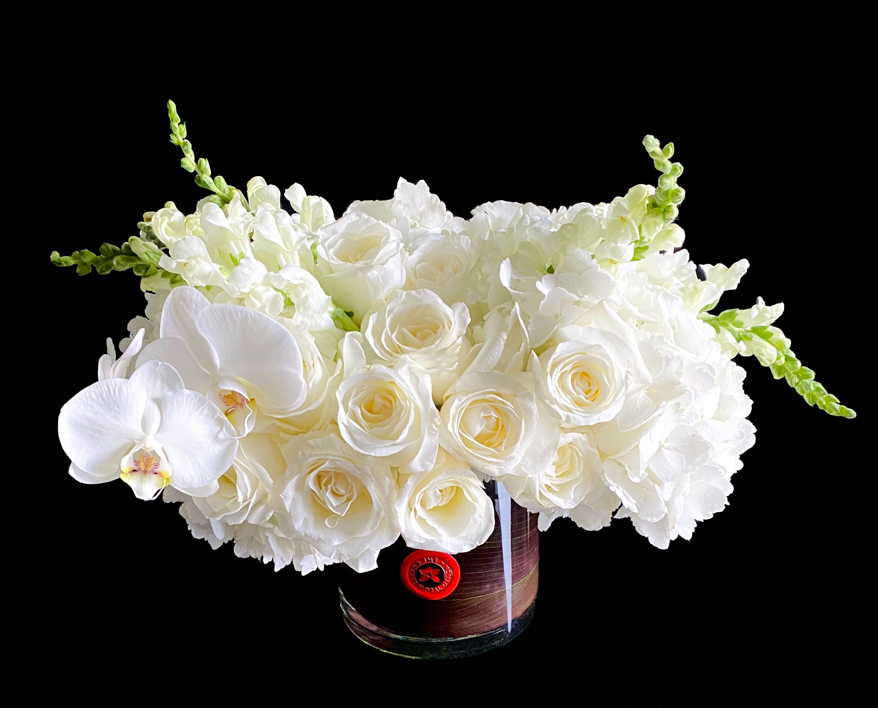 Classy Flowers - White blooms in wine leaf lined glass vase. Approximate measurements 15 inch wide by 10 inch H