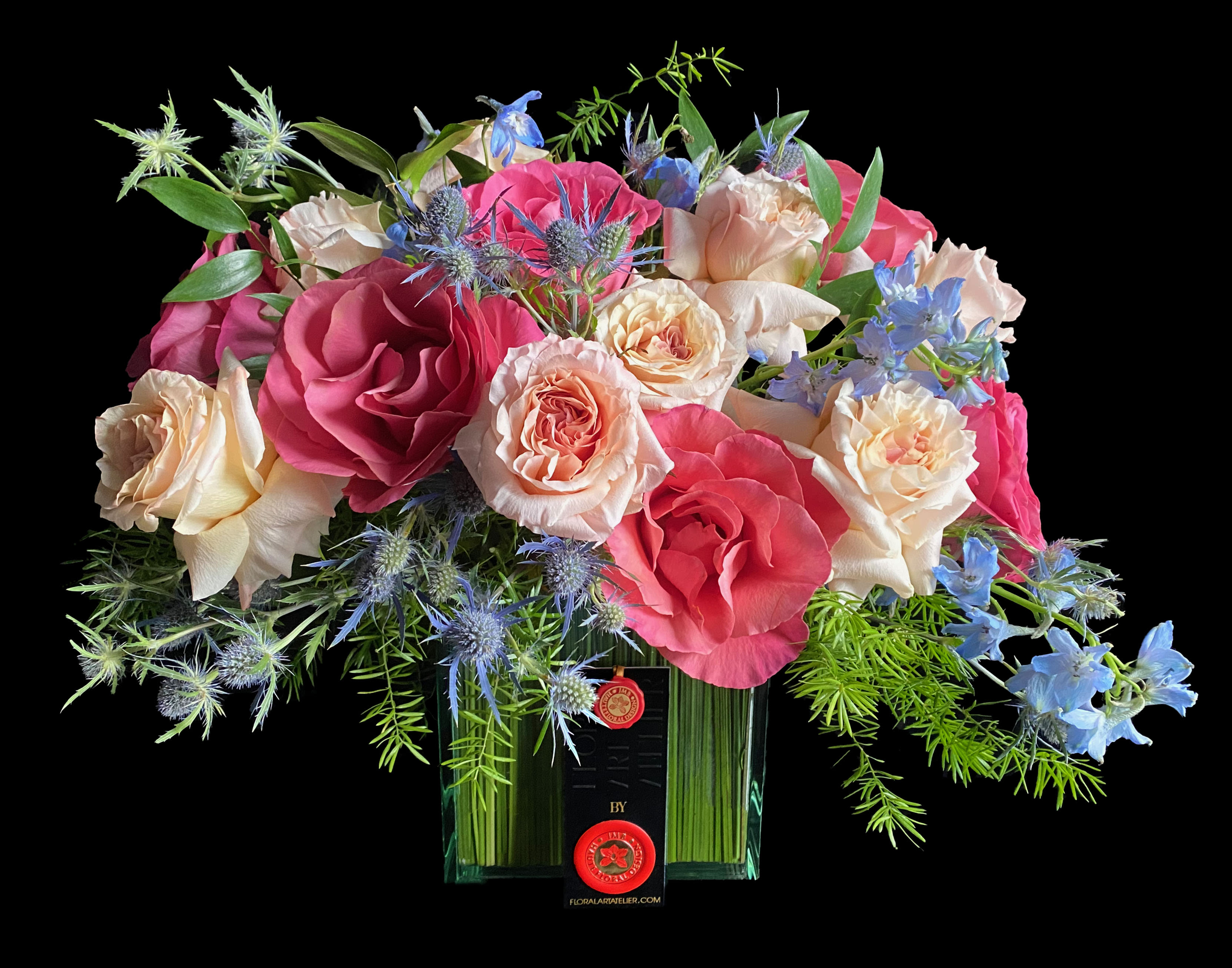 Bouquet of pink and cream roses with blue flowers in a glass vase