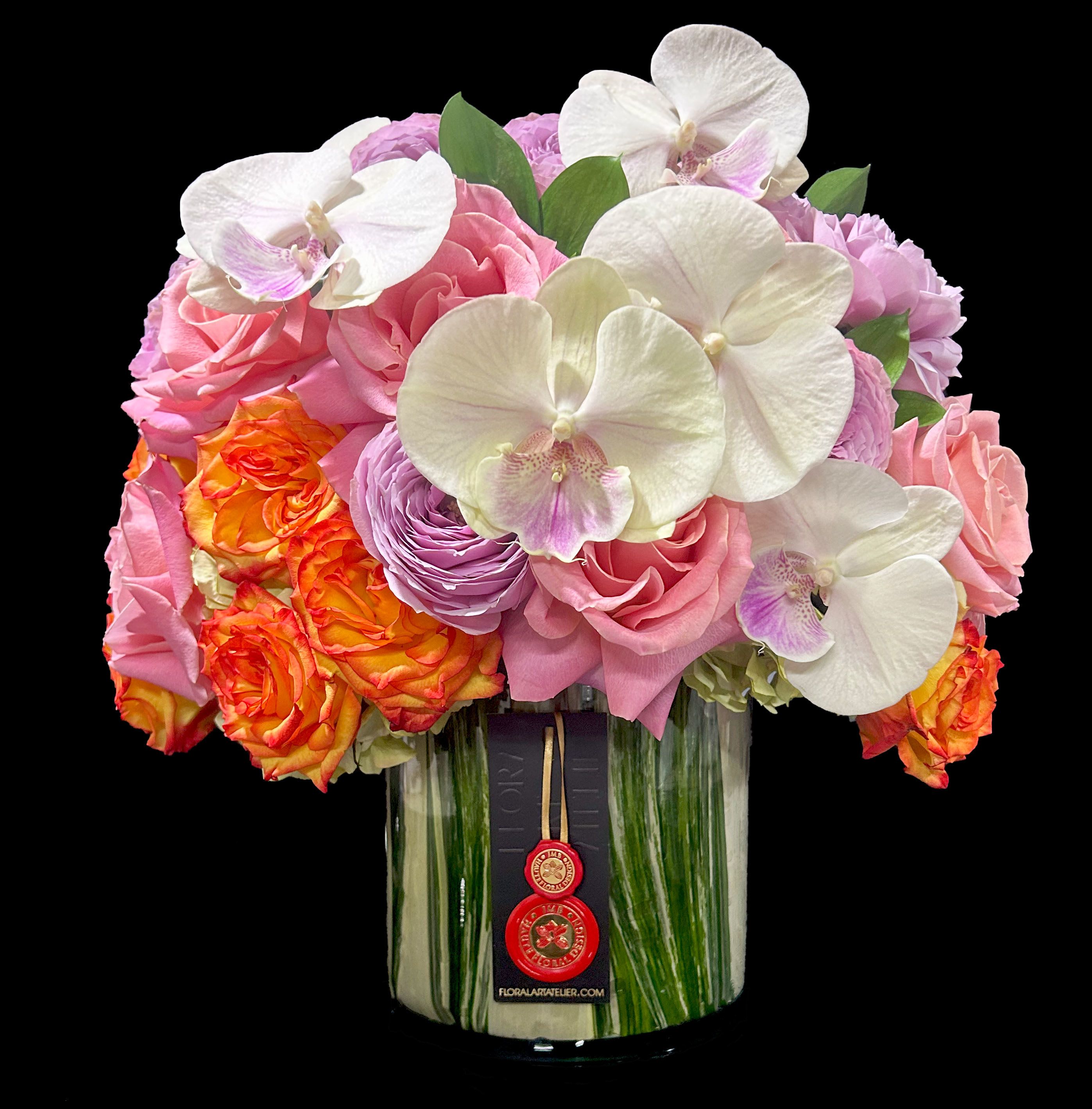 Compact arrangement of orchids and roses in a leaf-lined glass cylinder vase