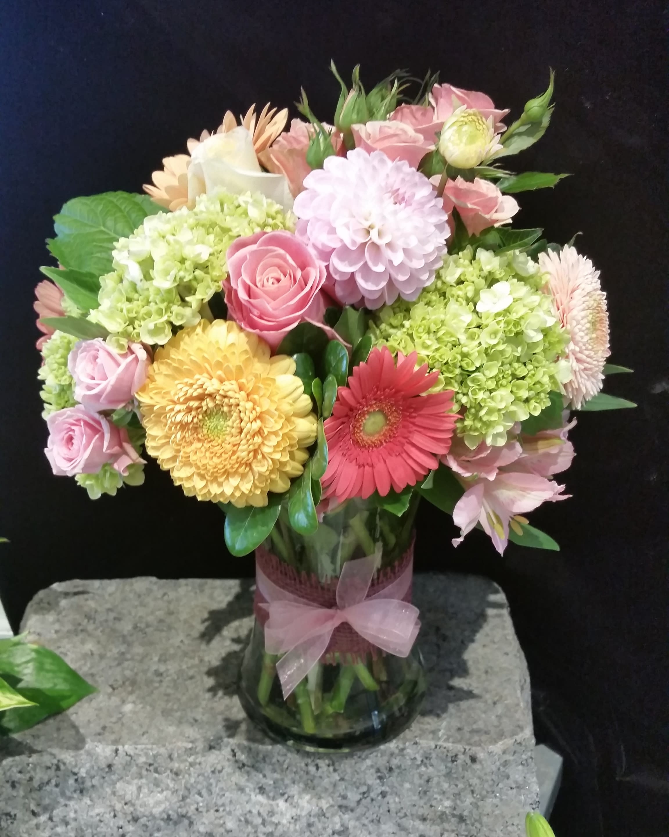 Summer Picnic - This is one of our bestsellers year-round, but especially in the summer when the dahlias and hydrangea are in season.  Practical, pretty, perfect for just about any occasion, the Summer Picnic is a lovely mix of subtle colored blooms like Gerbera Daisy, Dahlia, Hydrangea, and premium roses.  The finishing touch of ribbon around the gathering vase completes this picture of sweetness.  