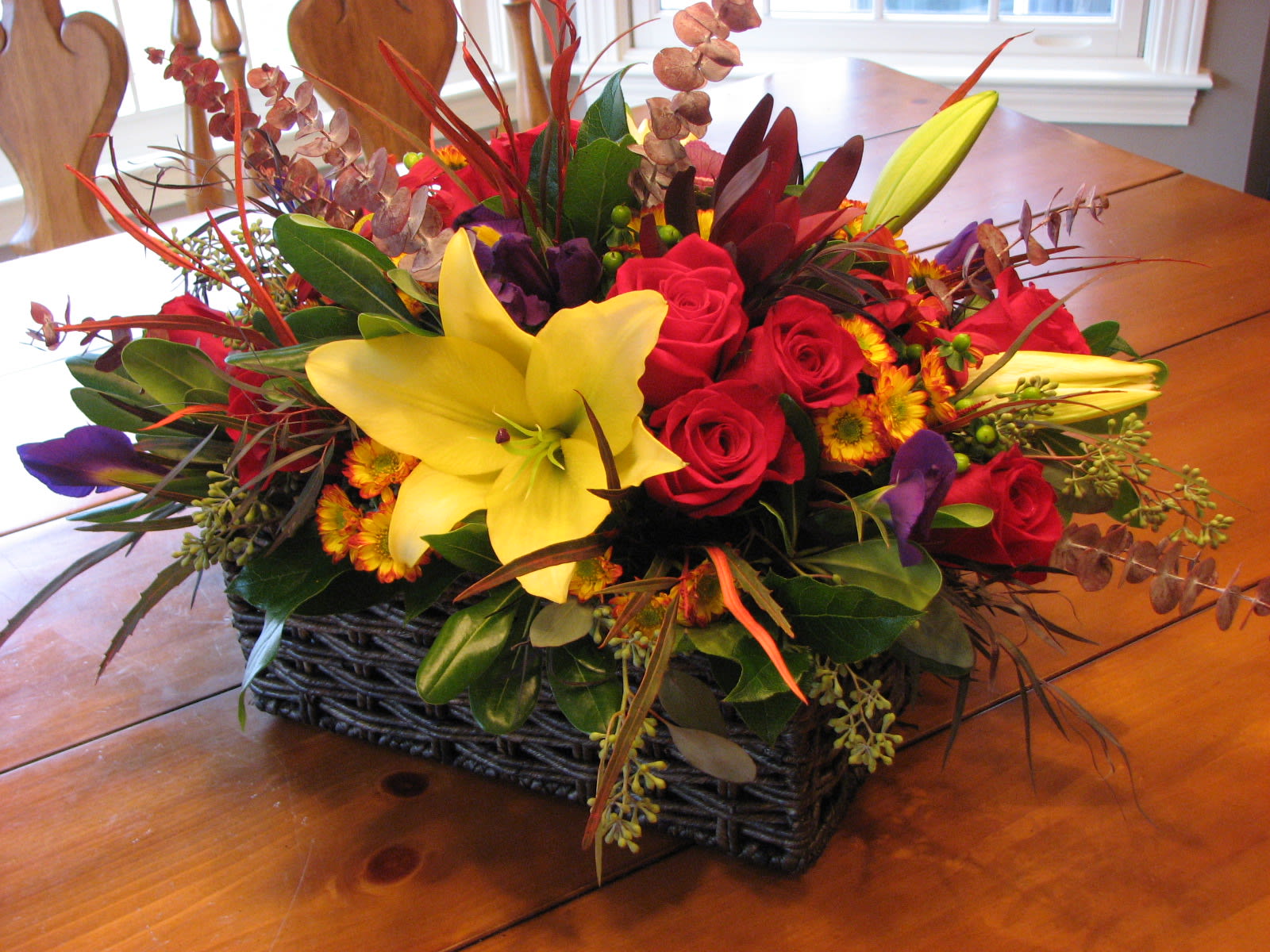 Mixed bouquet with yellow lilies and red roses in a woven basket