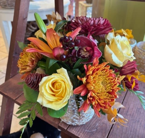 Mixed bouquet of roses, lilies, and chrysanthemums in a glass vase