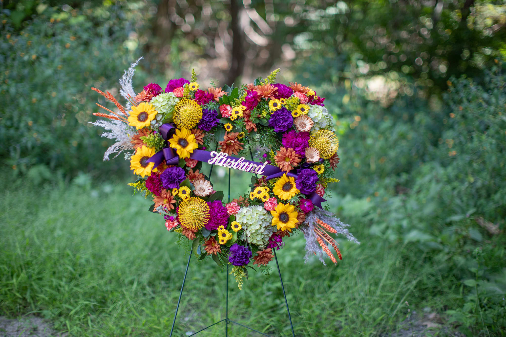 Autumnal Open Heart or Wreath - Matching our Autumnal Urn Wreath and Basket is a traditional set piece. Designed in the shape of a heart or circular wreath. Customized script is always available for sympathy and funeral floral designs. Design created by Katie Berger at Lucille's Floral Designs Inc.  