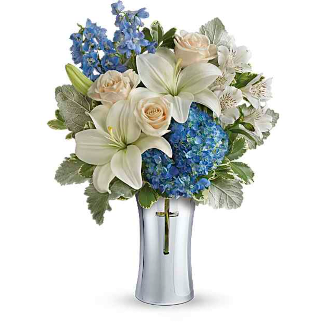 White lilies and roses with blue flowers in a clear glass vase