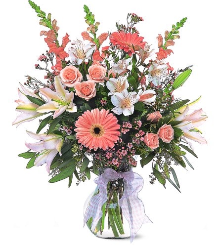 Bouquet of pink and white flowers in a glass vase with a lavender ribbon
