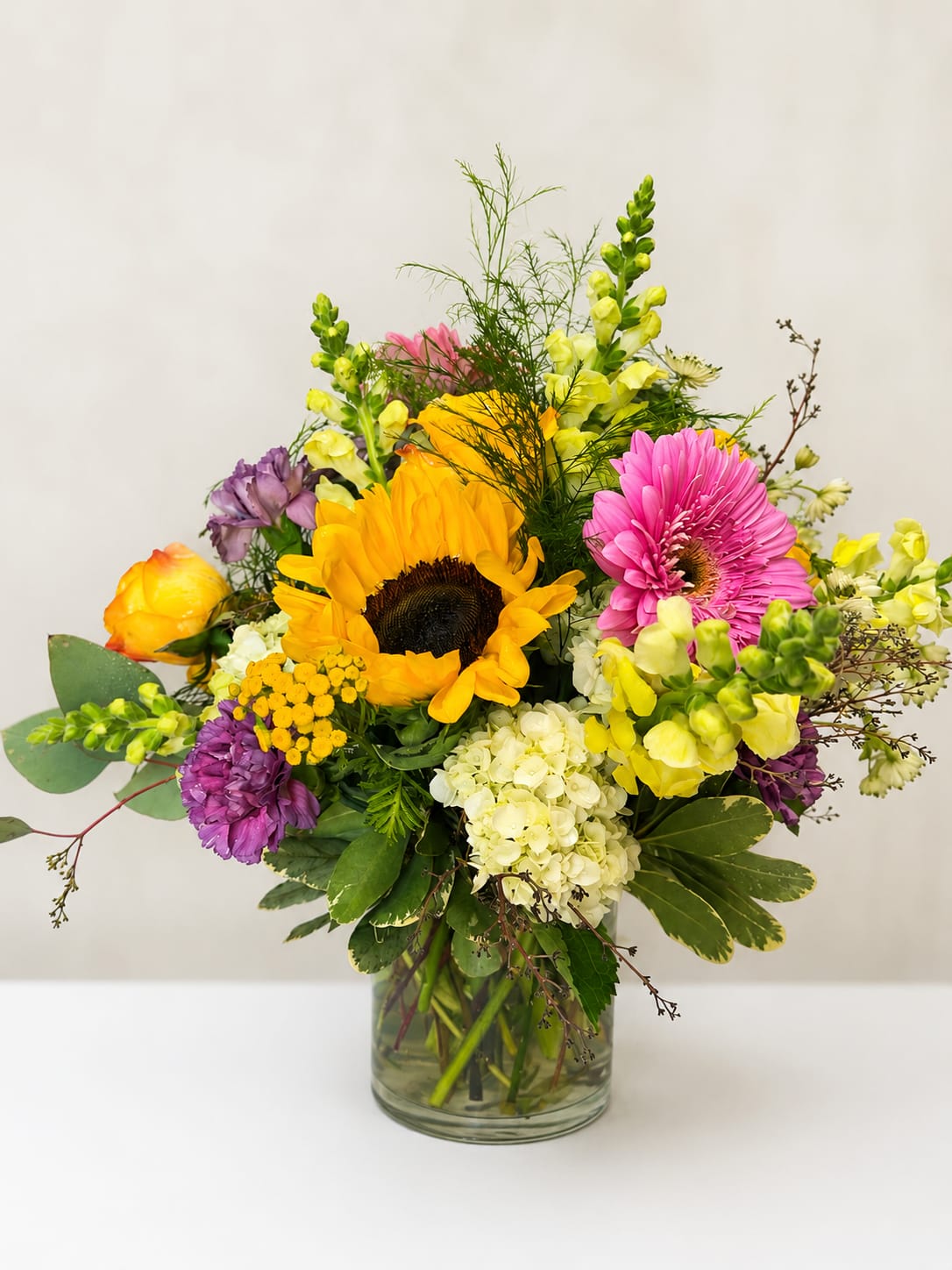 Summer Glow - Bring the warmth of Summer indoors! Designed with a vibrant mix of seasonal blooms in golden yellows, soft pinks, fresh whites, and lush greenery. This arrangement is bursting with texture and color, and is a joyful choice for birthdays, celebrations, thank-yous, or just because! Please note flowers are a natural product and variations do occur. Flower varieties may vary depending on seasonal availability while still maintaining the overall color palette and style.