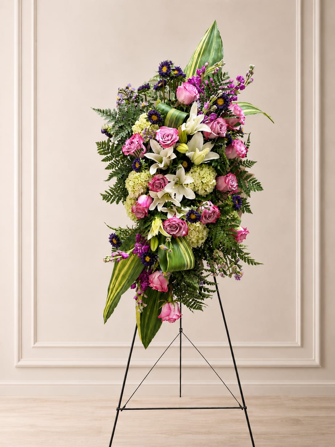 Graceful Remembrance - Soft and elegant, this standing spray is thoughtfully designed to honor a life with beauty and dignity. A harmonious blend of lavender roses, white lilies, hydrangeas, purple accents, and lush greenery creates a timeless expression of love, comfort, and lasting remembrance. Please note flowers are a natural product and variations can occur. Flower varieties may very depending on seasonal availability while still maintaining the overall color palette and style of the design.