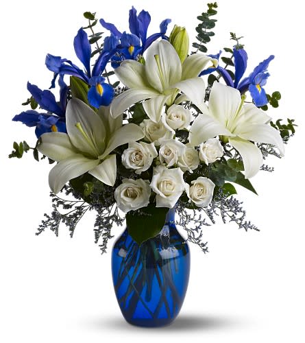White lilies, blue irises, and white roses in a blue glass vase