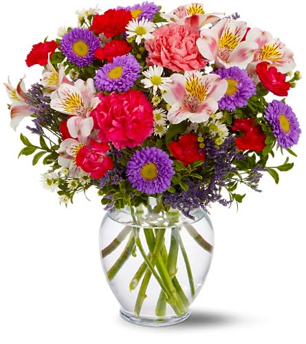 Mixed bouquet of pink, purple, and white flowers in a clear glass vase