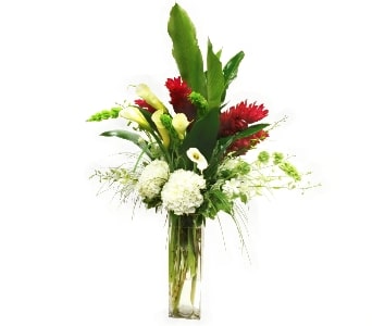 Tall floral arrangement with red, white, and green blooms in a clear glass vase